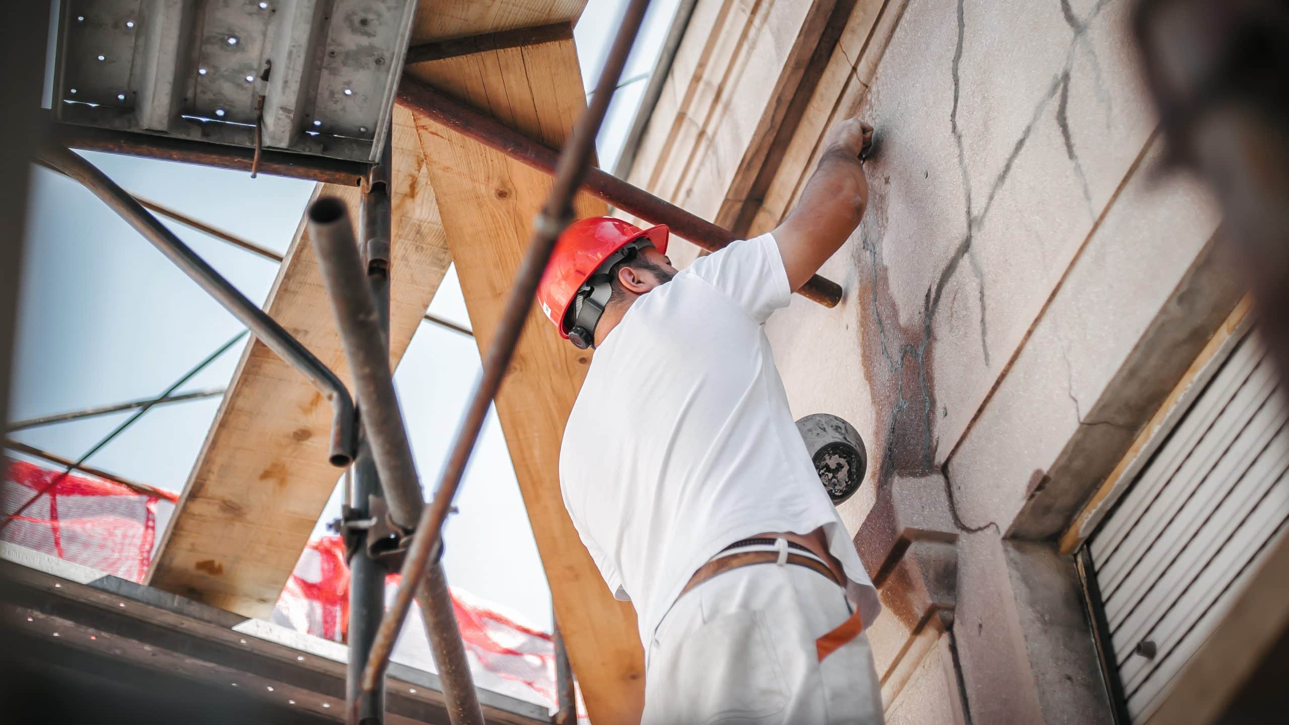 Man worker standing on scaffolding and restore old building facade Man worker standing on scaffolding, perform work on the restoration of the facade of the old building. Repairing and renovate